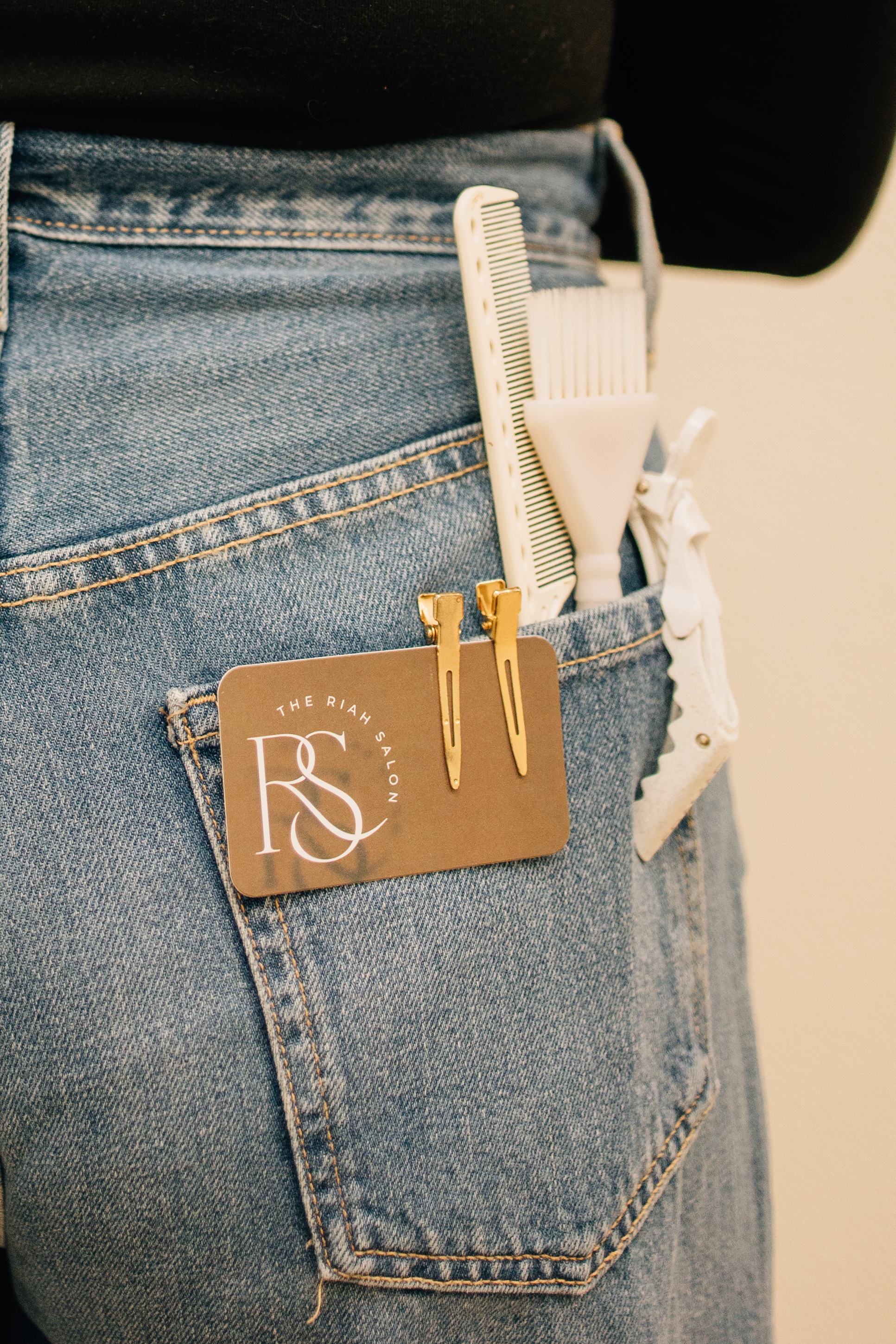 Riah Salon card, comb and styling tools tucked into a denim pocket