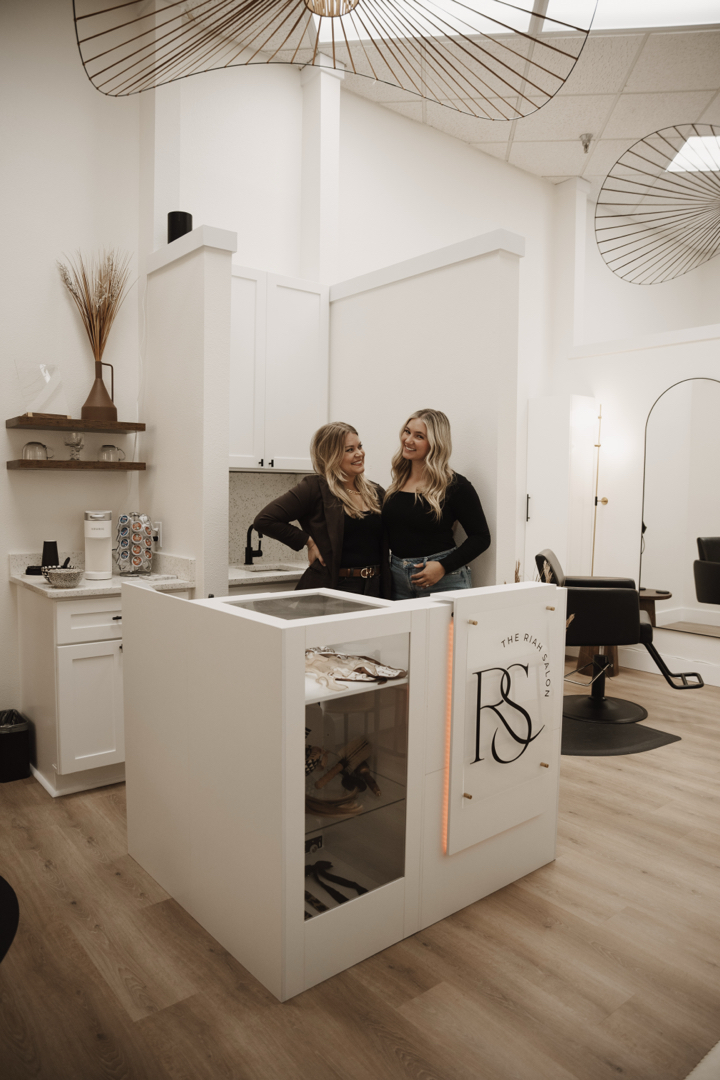 Katie and Emily together at the reception desk inside The Riah Salon